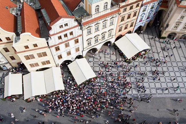Vista aérea de una plaza con muchas personas y carpas. Edificios históricos alrededor.