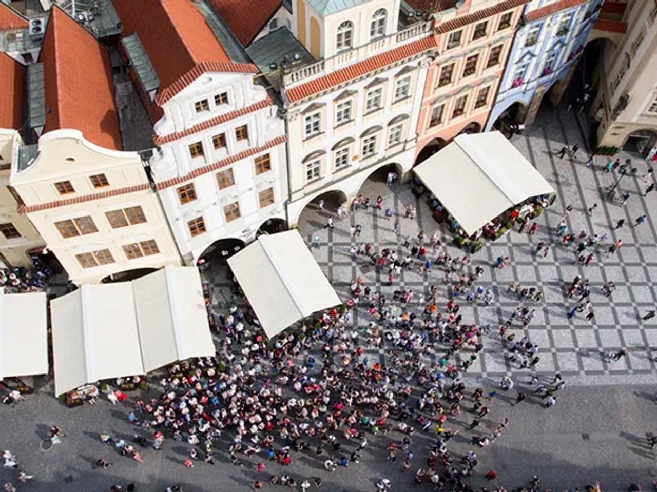 Vista aérea de una plaza con muchas personas y carpas. Edificios históricos alrededor.