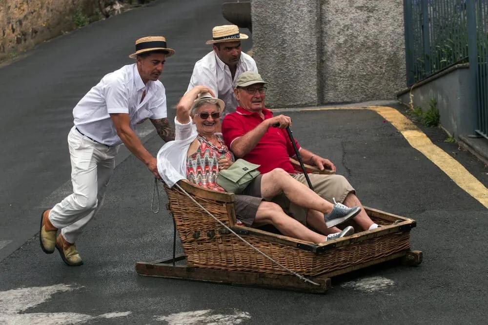 dois homens empurram um carro de cesto com turistas