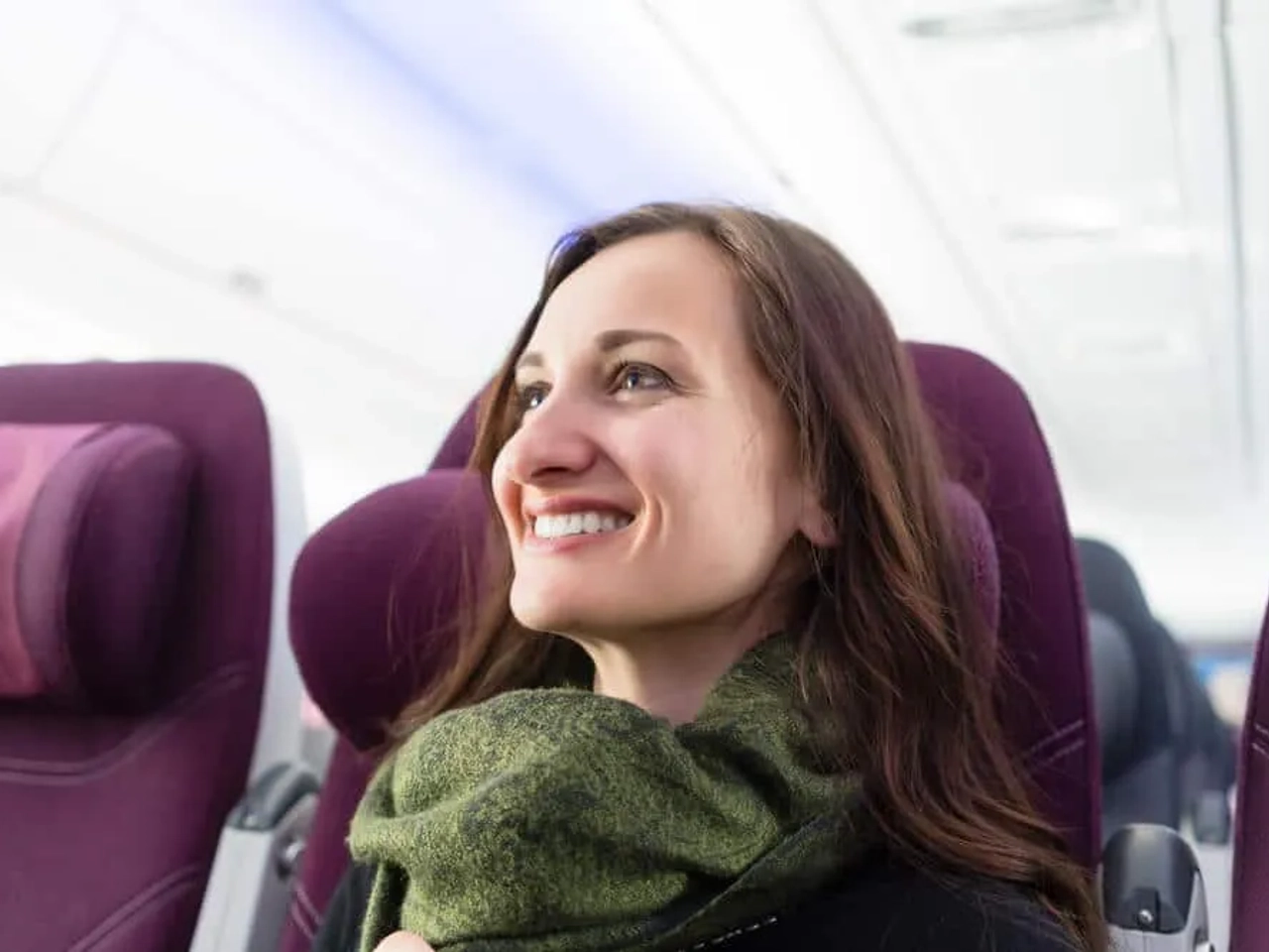mulher com cachecol verde sentada num aviao