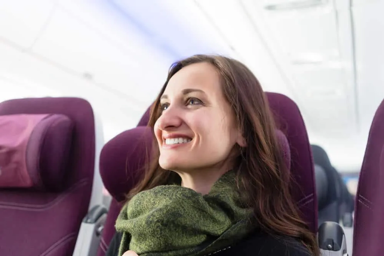 mulher com cachecol verde sentada num aviao