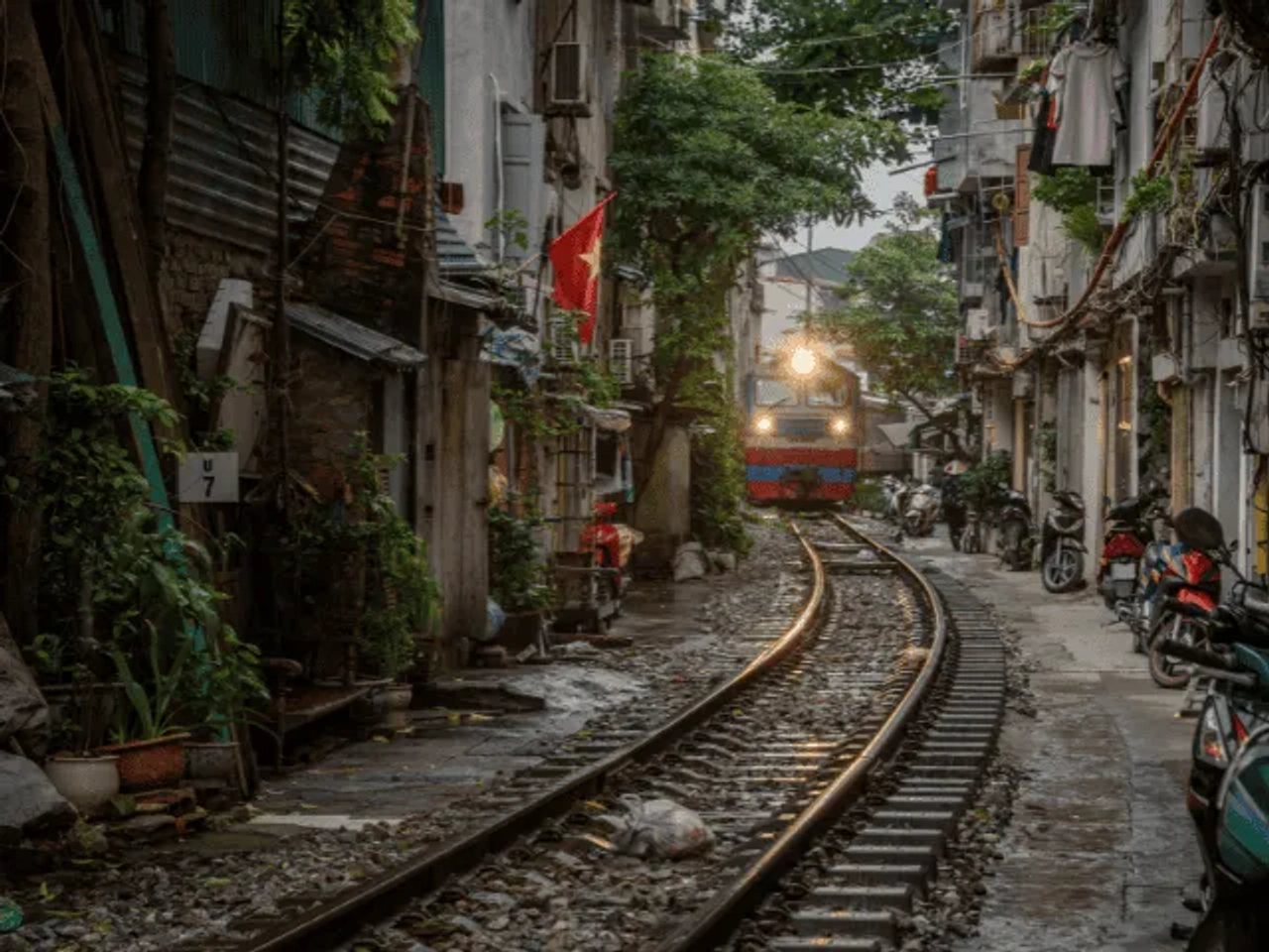 comboio numa linha ferroviaria junto a casas em hanoi no vietname
