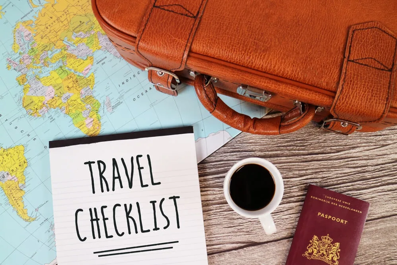 checklist, cafe e mala pousados em cima de um mapa mundo