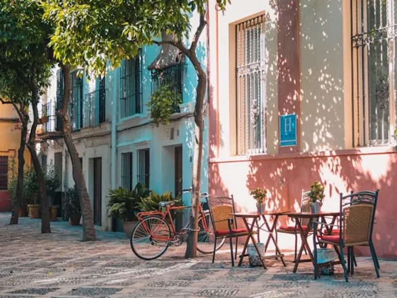casinhas coloridas com uma bicicleta encostada e um café em santa cruz, sevilha, espanha