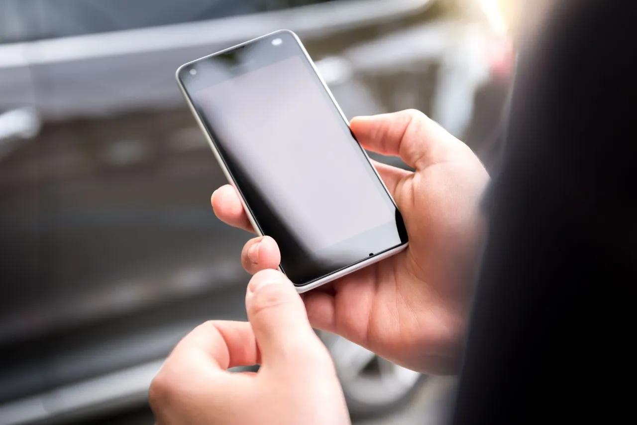 Mani che tengono uno smartphone durante la compilazione dell’ESTA Mobile per un viaggio negli Stati Uniti.