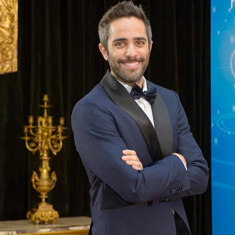 Hombre sonriente en traje de gala, posando en un evento elegante.