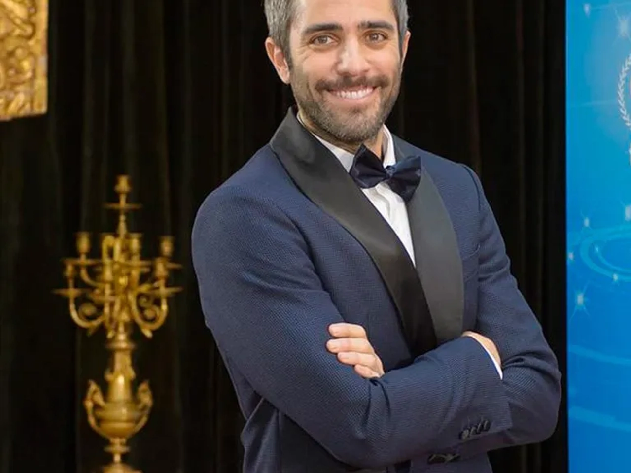 Hombre sonriente en traje de gala, posando en un evento elegante.