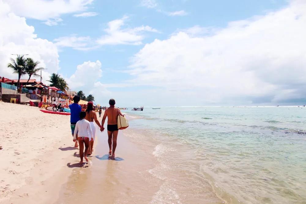 familia passeia por uma praia de Maceió