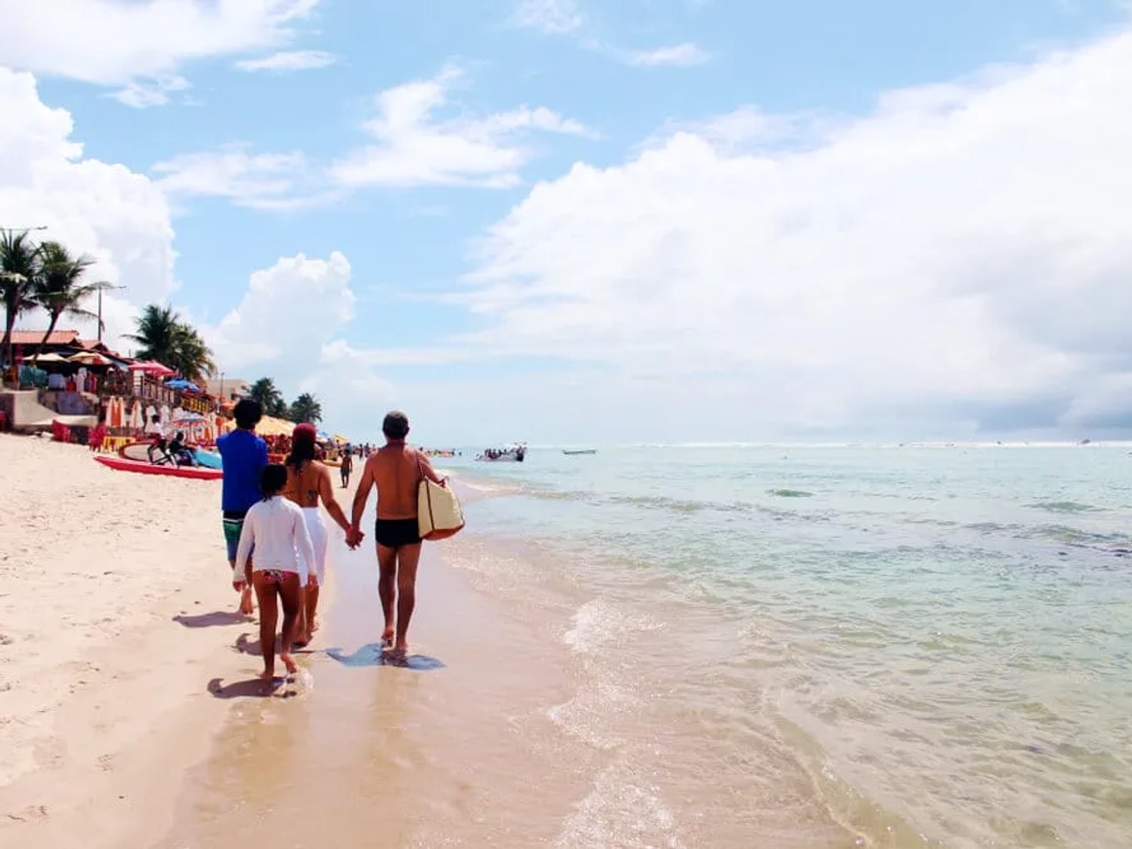 familia passeia por uma praia de Maceió