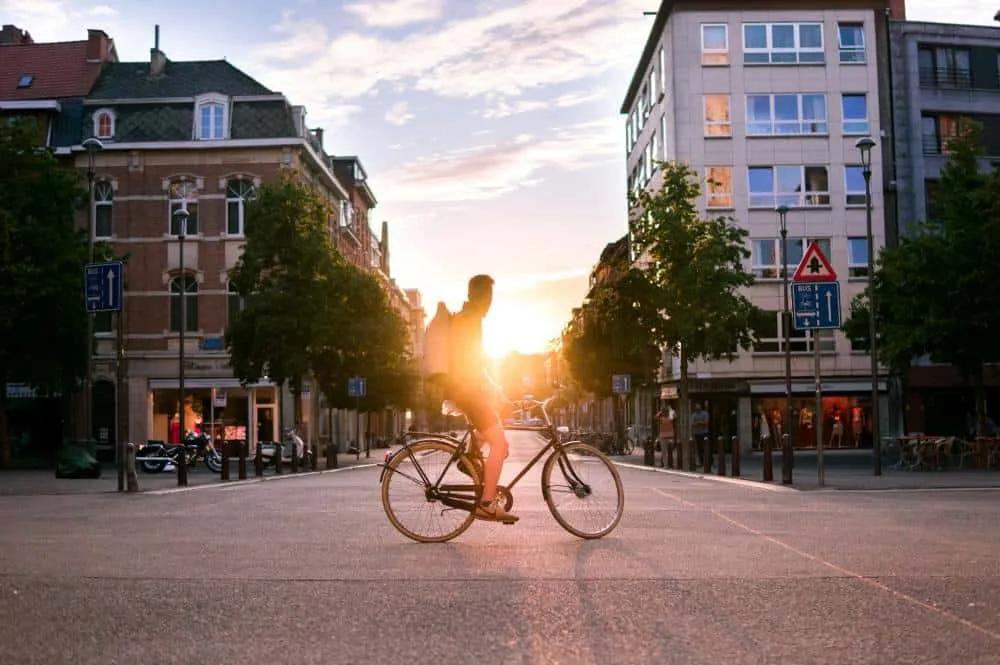 Ciclista pedaleando en una calle urbana al atardecer en Bélgica.