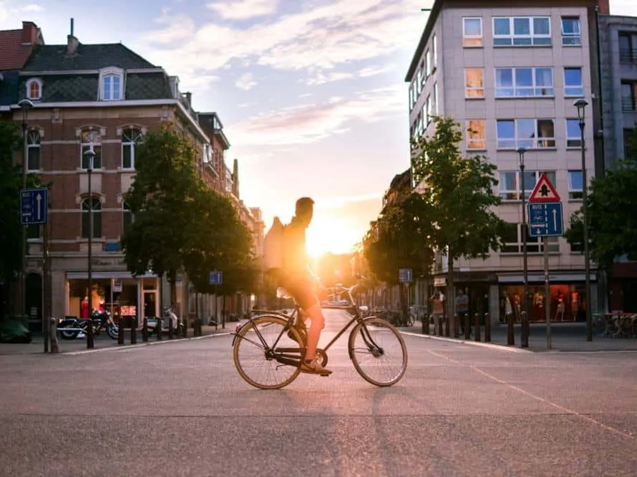Ciclista pedaleando en una calle urbana al atardecer en Bélgica.