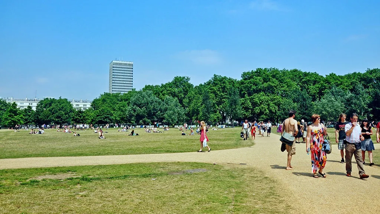 Parque em Londres com pessoas caminhando e relaxando em um dia ensolarado.