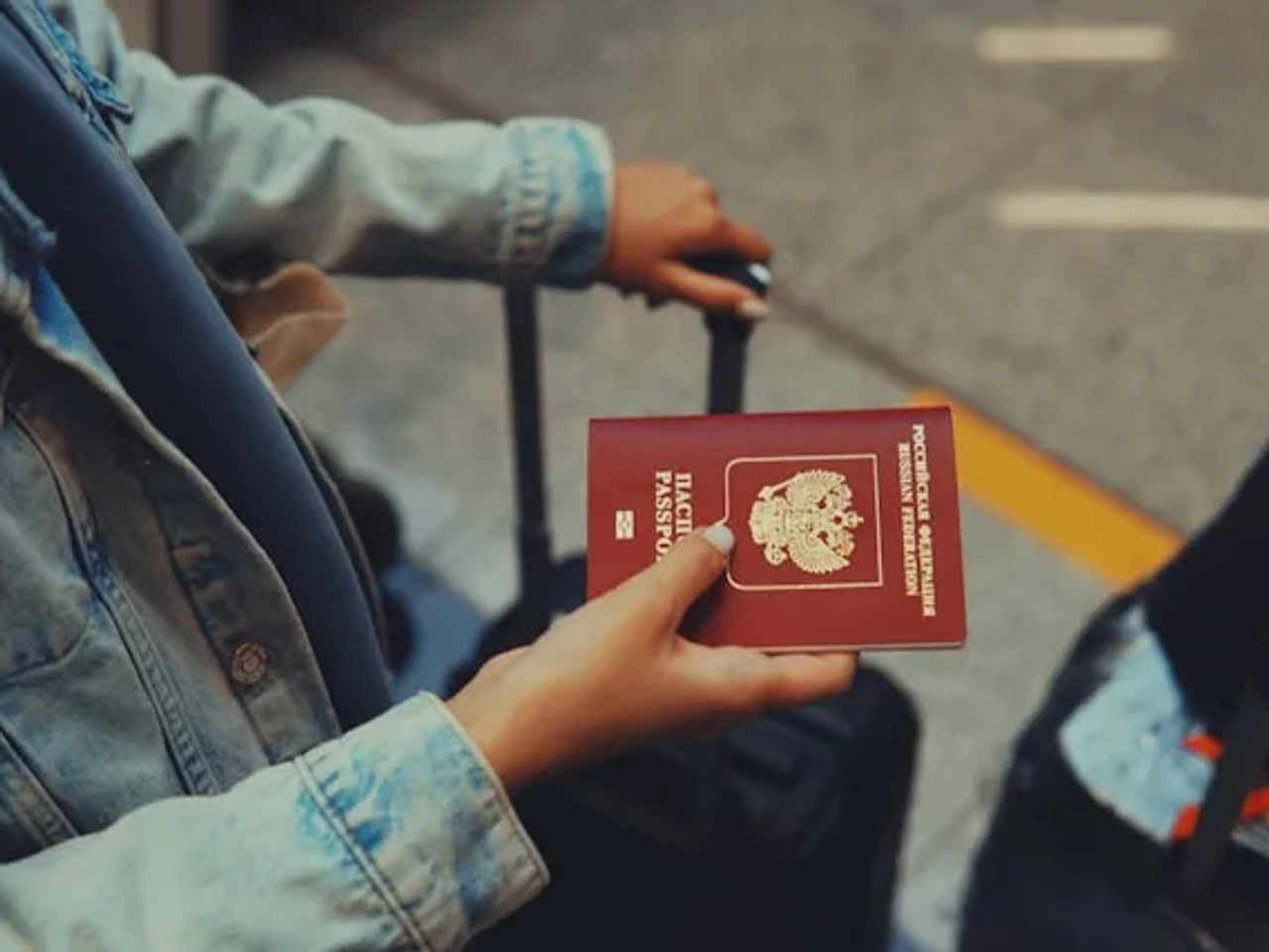 pessoa a segurar uma mala de viagem e um passaporte no aeroporto