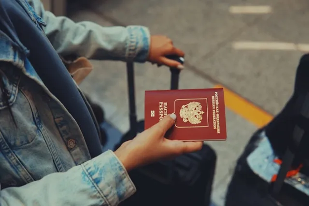 pessoa a segurar uma mala de viagem e um passaporte no aeroporto