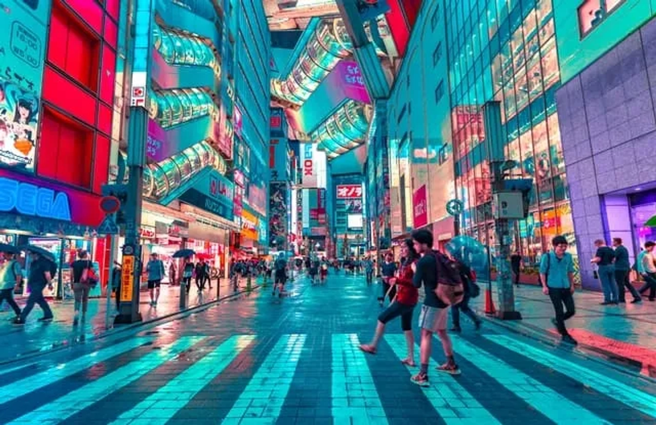 Veduta notturna di una strada illuminata a Tokyo, con insegne colorate, grattacieli e persone che camminano tra i quartieri moderni della città.