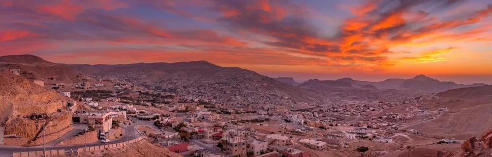 Vista panorâmica de Petra ao pôr do sol, destacando montanhas e construções históricas.