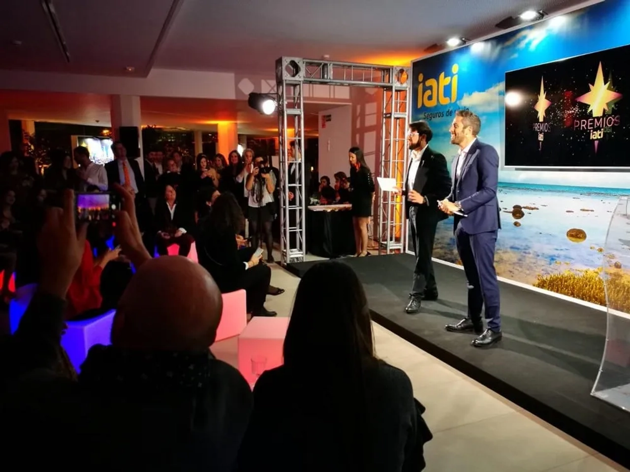 Ceremonia de entrega de los Premios IATI con presentadores y público atento.