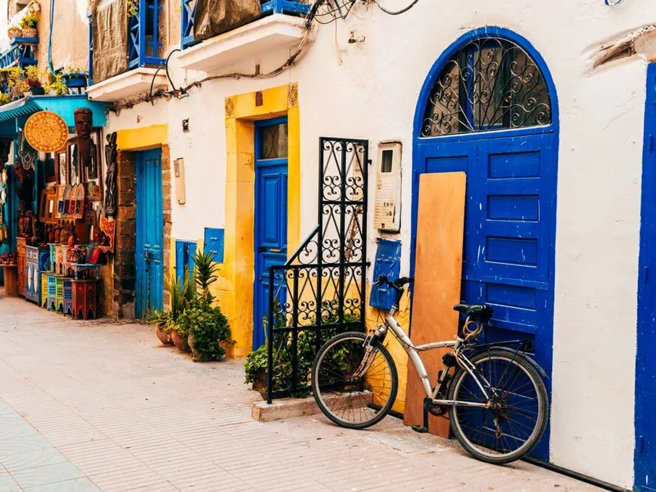 rua colorida de essaouira com bicicleta parada em frente de uma porta azul