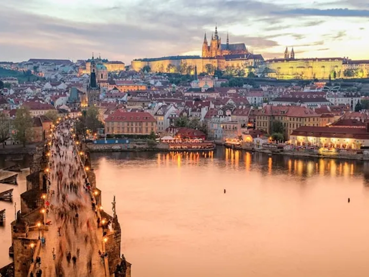pessoas a passear na ponte carlos em praga ao por do sol