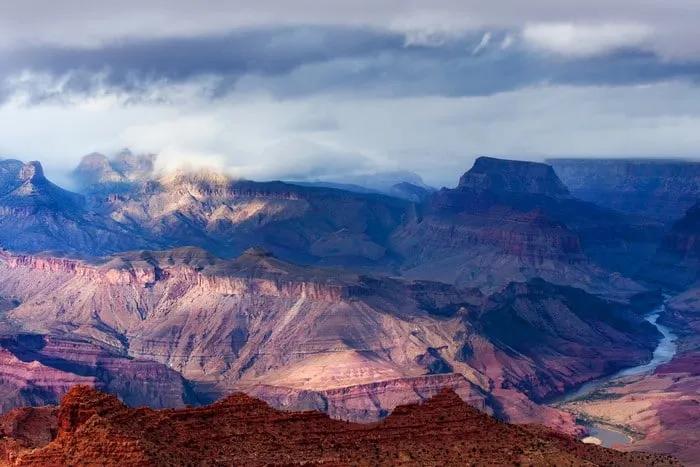 Vista panorámica del Gran Cañón con nubes y ríos serpenteantes.