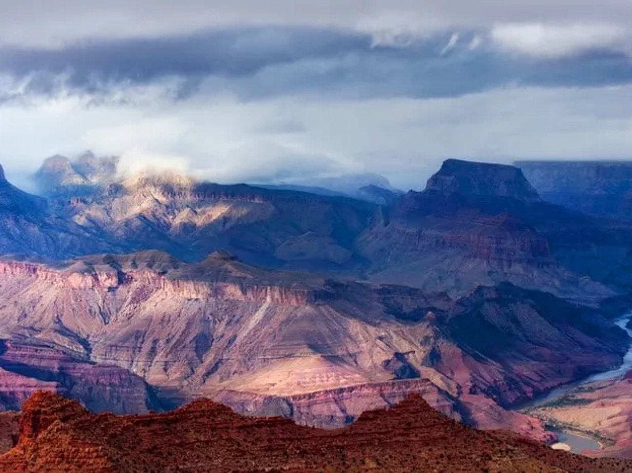Vista panorámica del Gran Cañón con nubes y ríos serpenteantes.