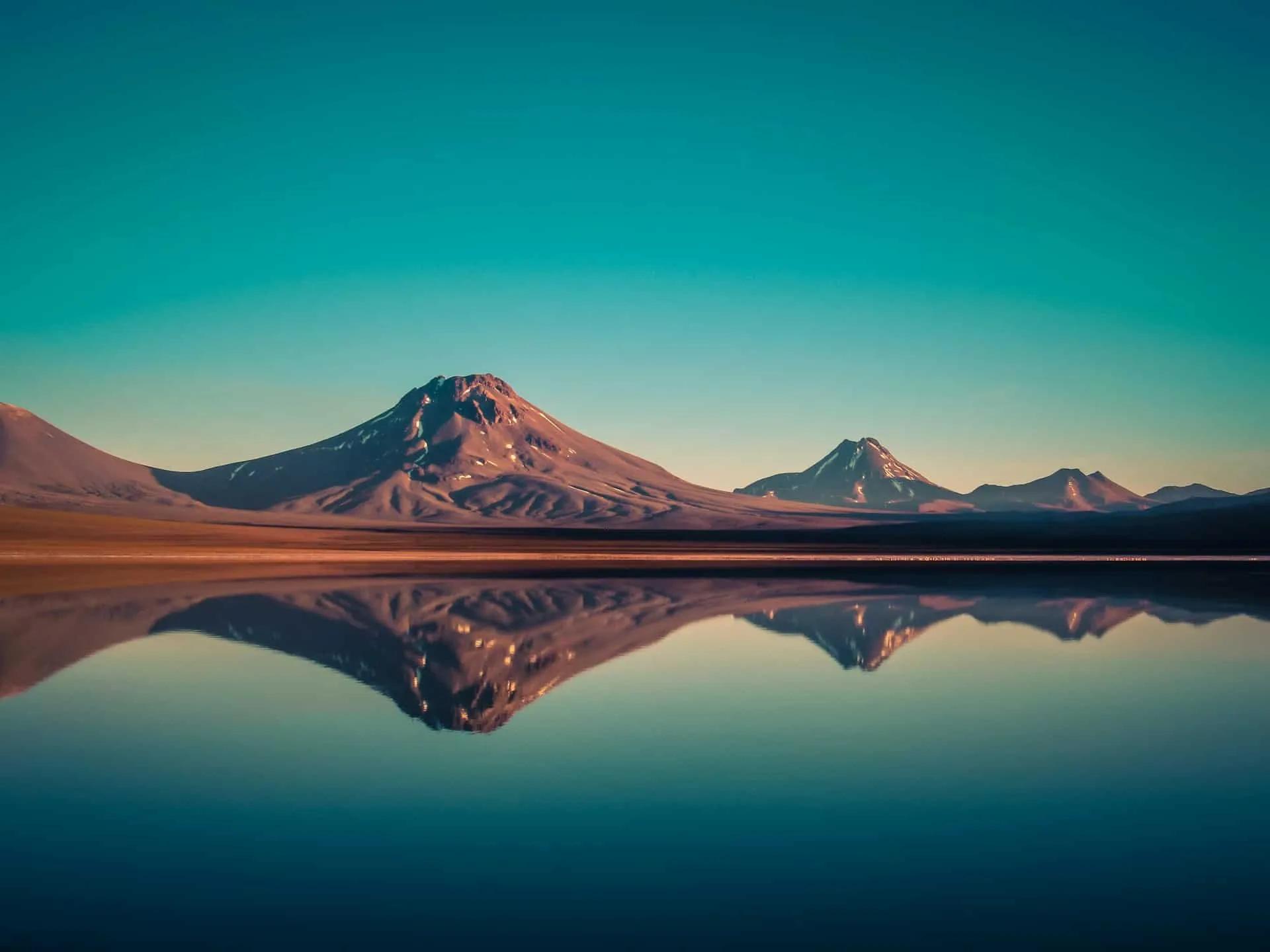 Paisagem montanhosa refletida em lago, destacando a beleza natural do Chile.
