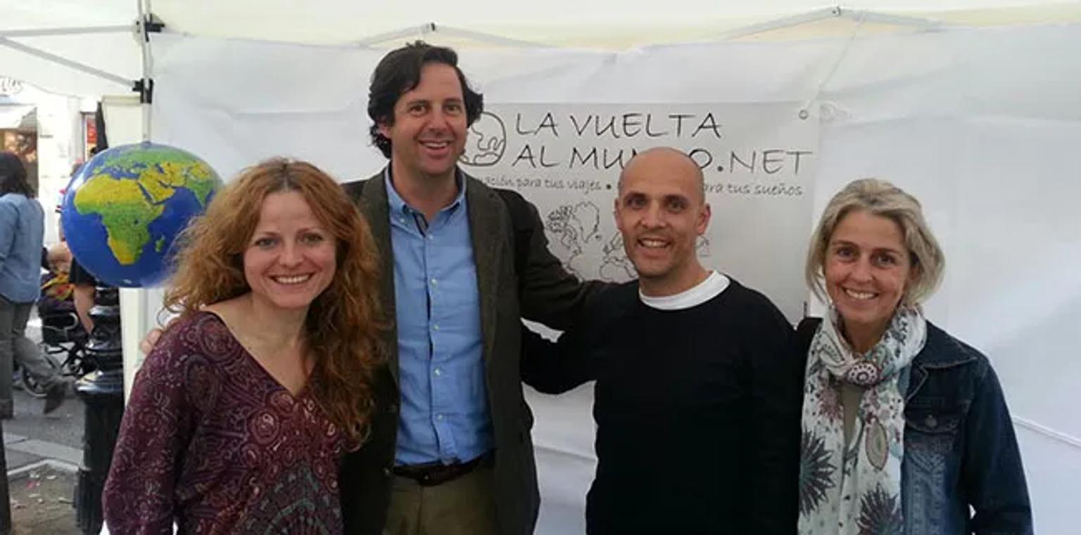 Cuatro personas sonrientes posan frente a un fondo con un mapa y un logo.