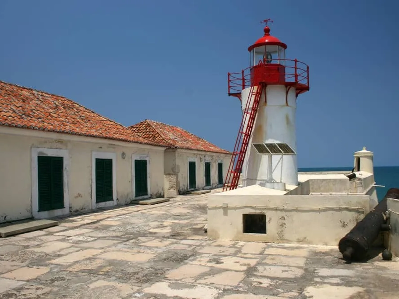 farol vermelho e branco e casas no interior doe forte de sao sebastiao