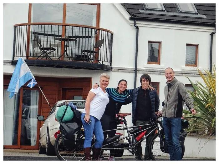 Cuatro personas posan junto a una bicicleta en un entorno urbano.