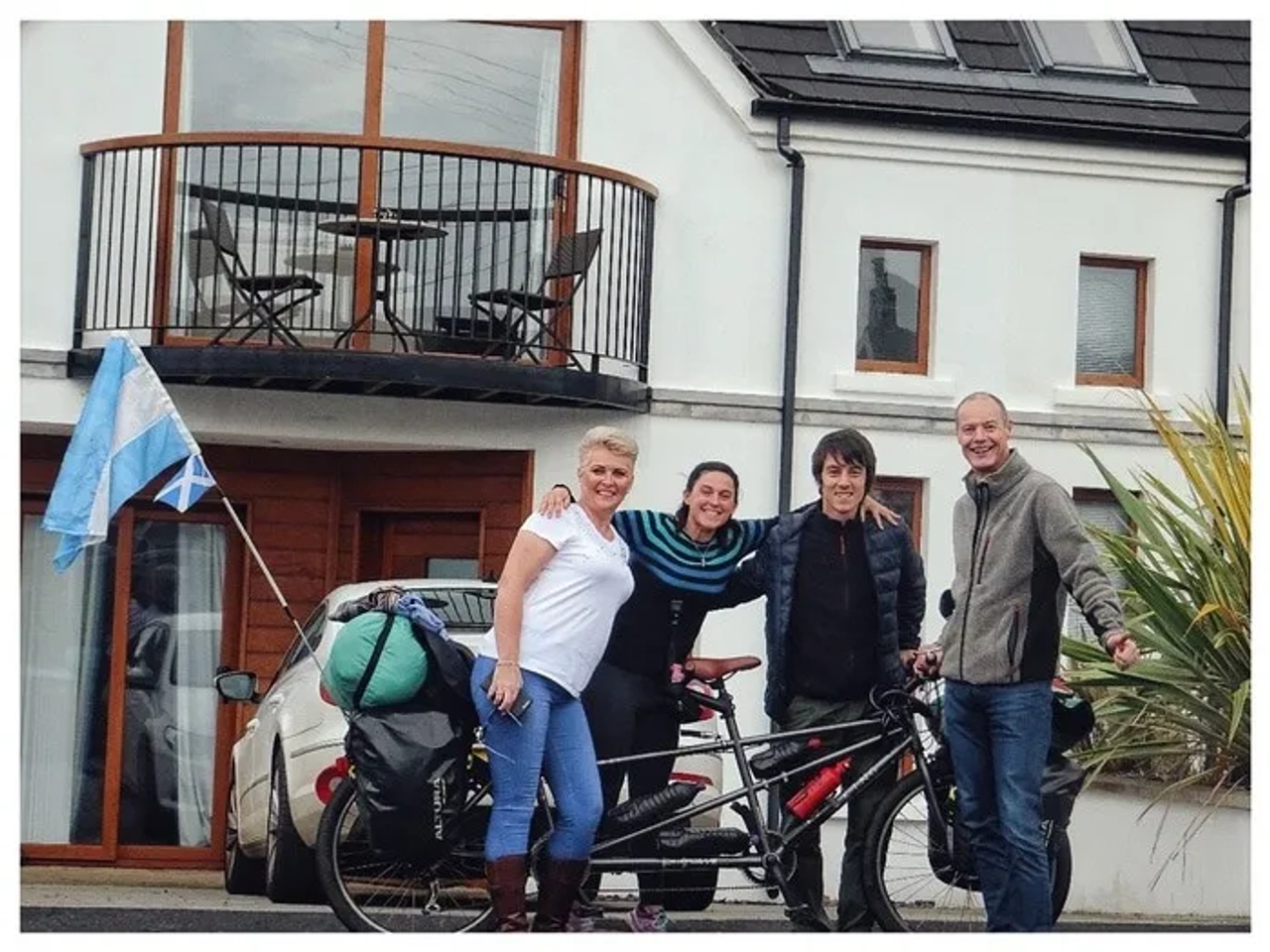 Cuatro personas posan junto a una bicicleta en un entorno urbano.