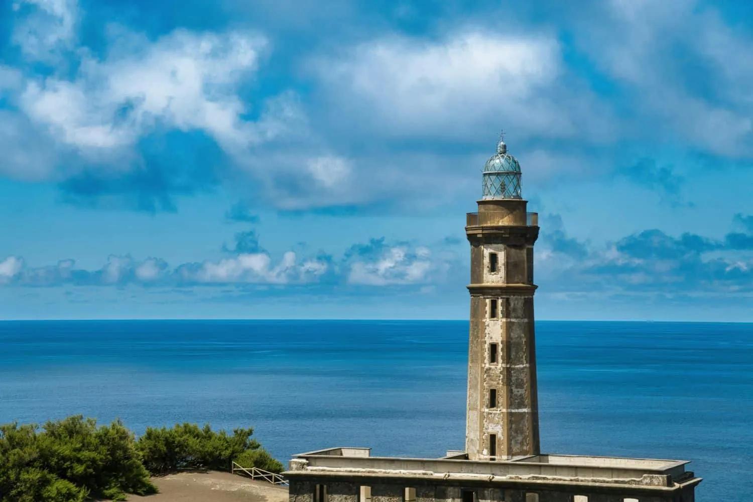 Farol à beira-mar com céu azul e nuvens, em São Miguel, Açores.