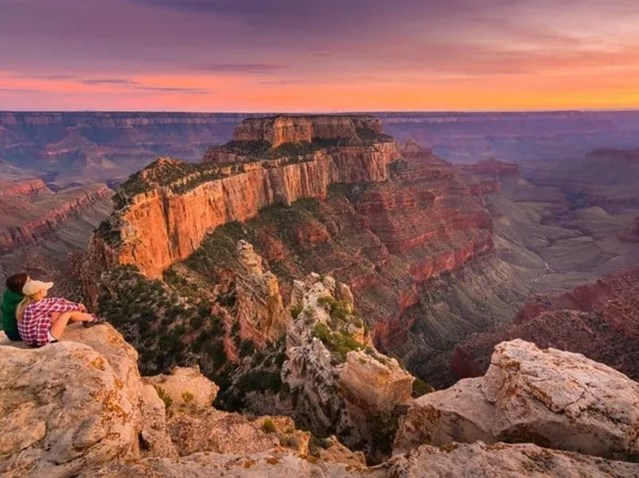 Pareja admirando el paisaje del Gran Cañón al atardecer.
