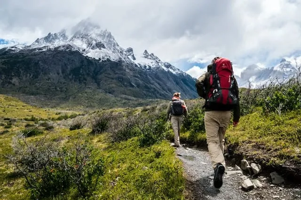dois mochileiros a andar por montanha