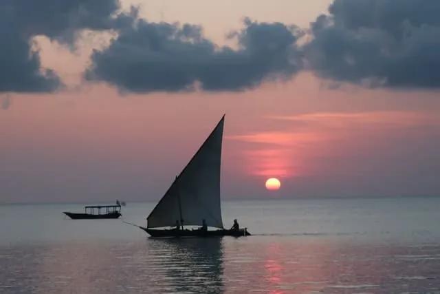 pessoas em pequeno barco durante o por do sol em zanzibar