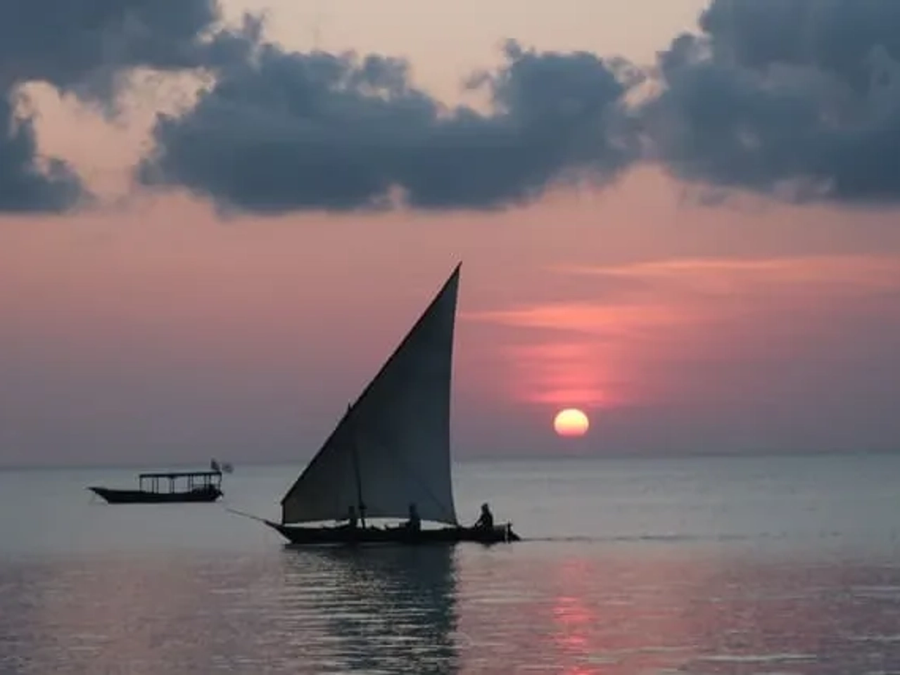 pessoas em pequeno barco durante o por do sol em zanzibar