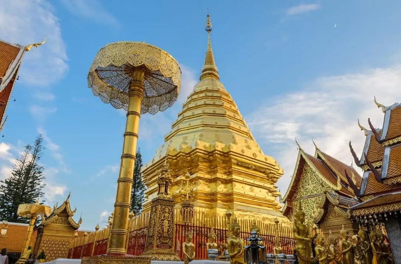 Tempio dorato a Chiang Mai, con stupa e decorazioni tradizionali thailandesi sotto un cielo azzurro.