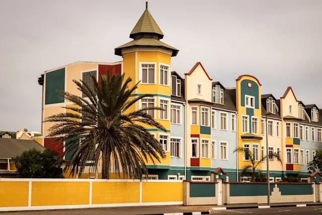 casa amarela, verde, azul, vermelha com uma plameira em Swakopmund na namibia