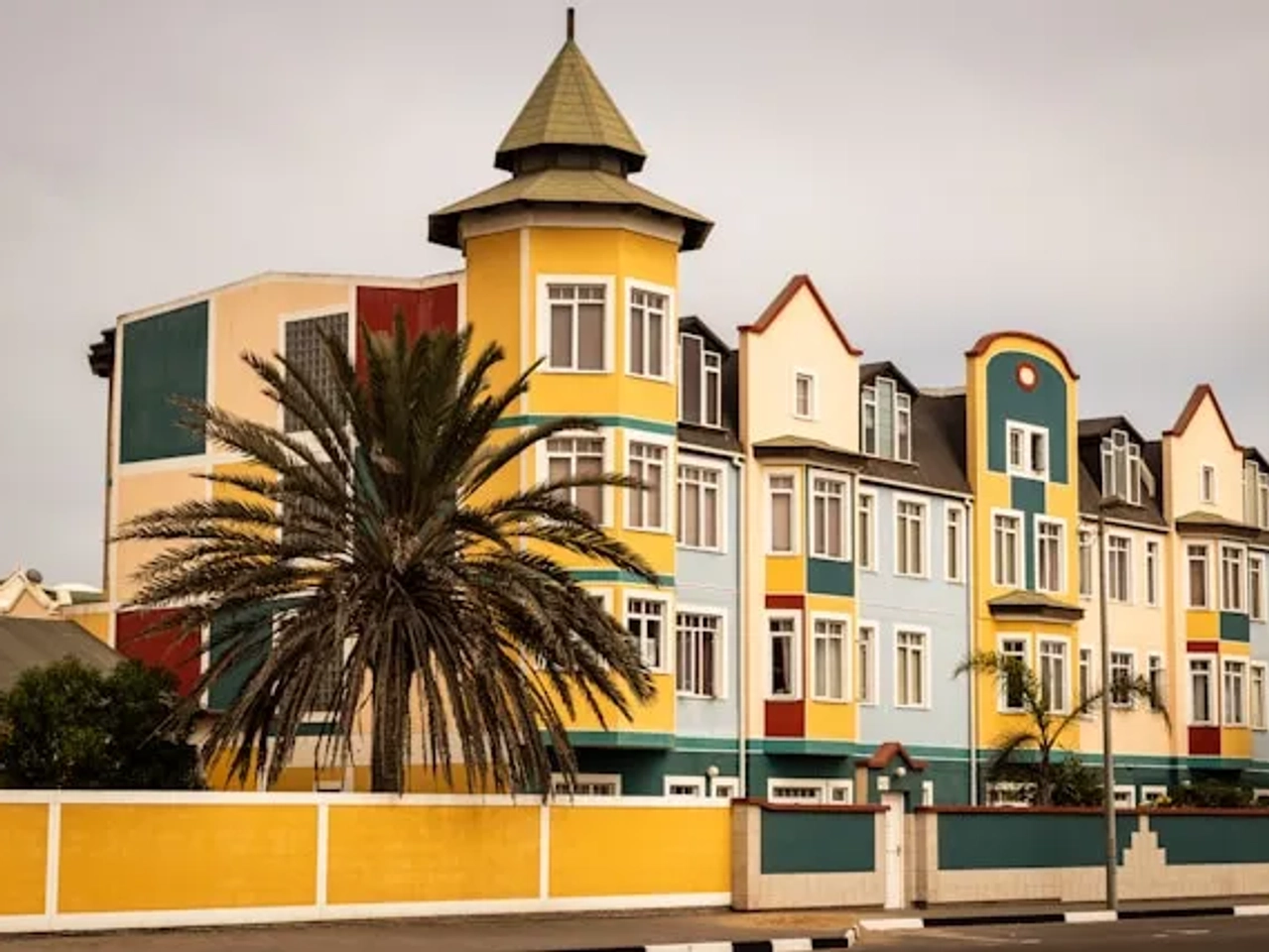 casa amarela, verde, azul, vermelha com uma plameira em Swakopmund na namibia