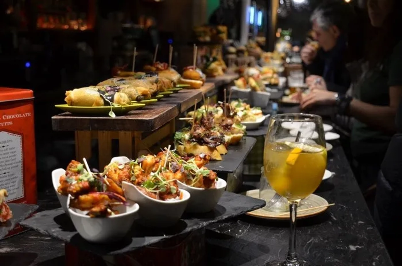 Mesa con variedad de pintxos y una bebida en un bar de Bilbao.
