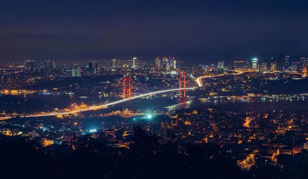 Vista noturna de Istambul, destacando a ponte iluminada e a cidade ao fundo.