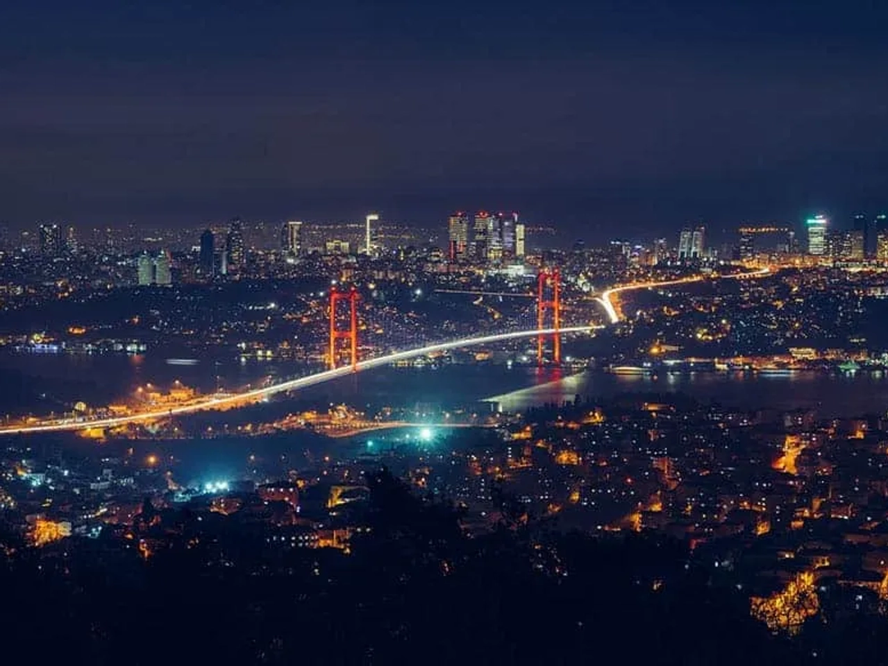 Vista noturna de Istambul, destacando a ponte iluminada e a cidade ao fundo.