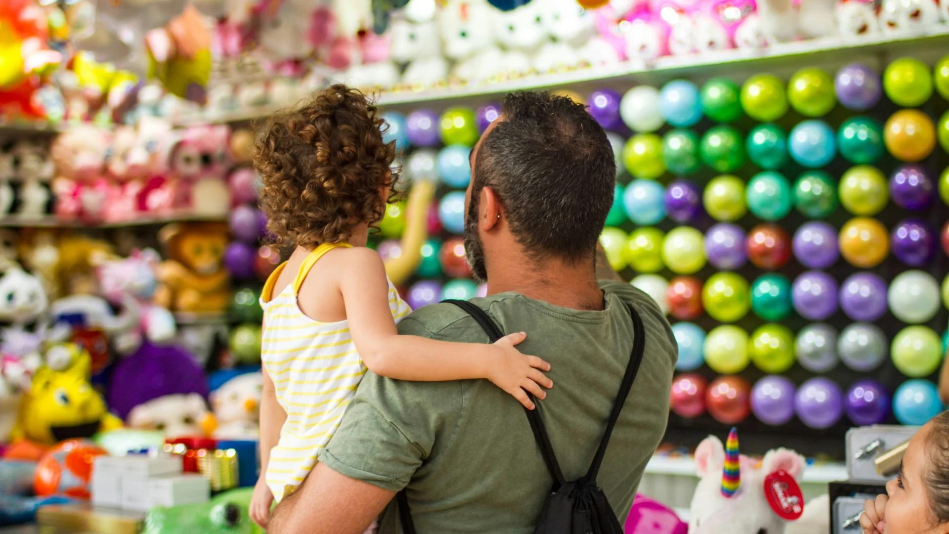 Padre comprando juguetes a su hija con una tarjeta de crédito sin vinculación a un seguro de vida.