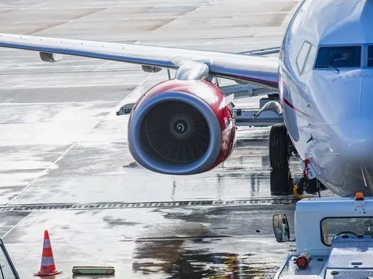 Avião estacionado no aeroporto, com foco no motor e na asa.