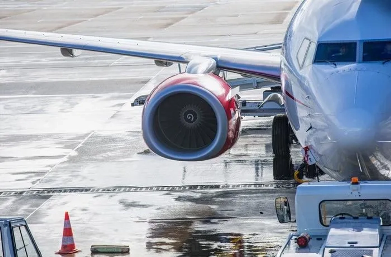 Avião estacionado no aeroporto, com foco no motor e na asa.
