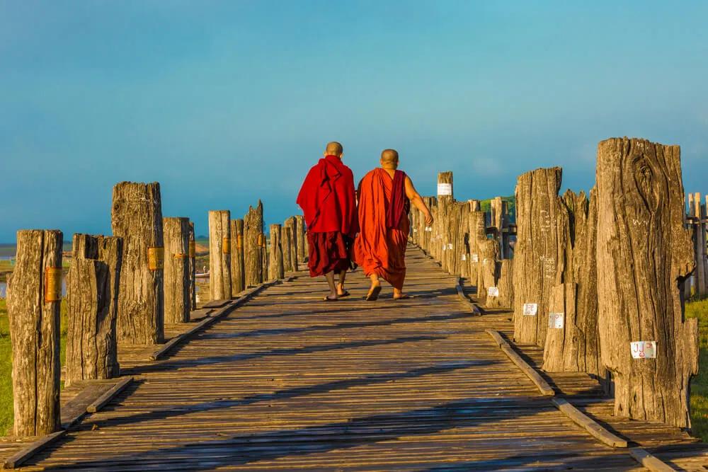 dois monges caminham numa ponte de madeira