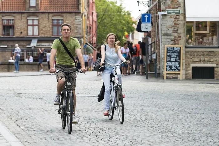 Pareja montando bicicletas en una calle empedrada de Bélgica.
