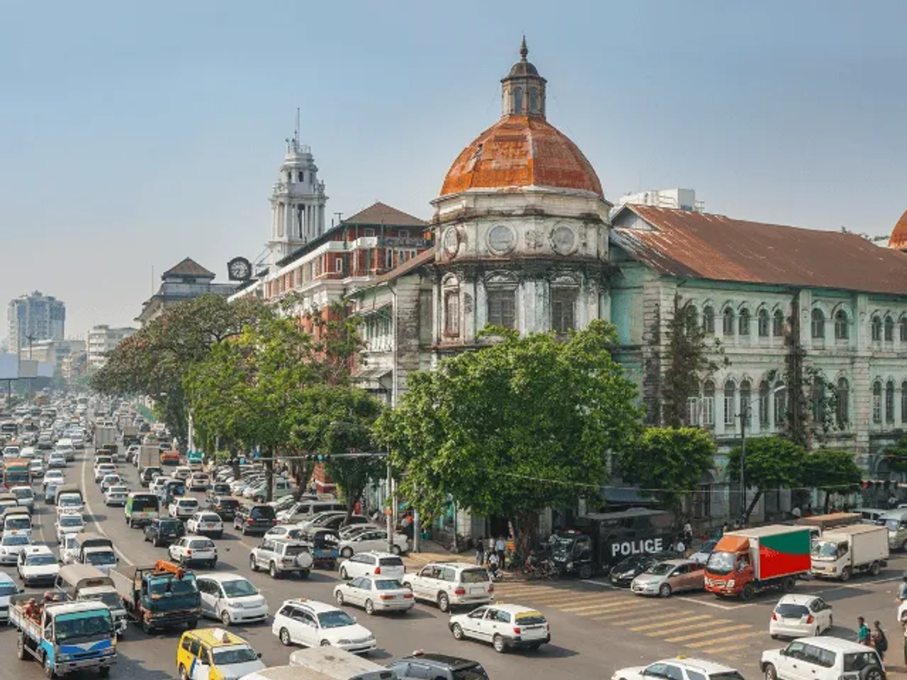 muitos carros numa estrada junto a um edificio grande com cupulas no telhado em Yangon, Myanmar no sudeste asiatico