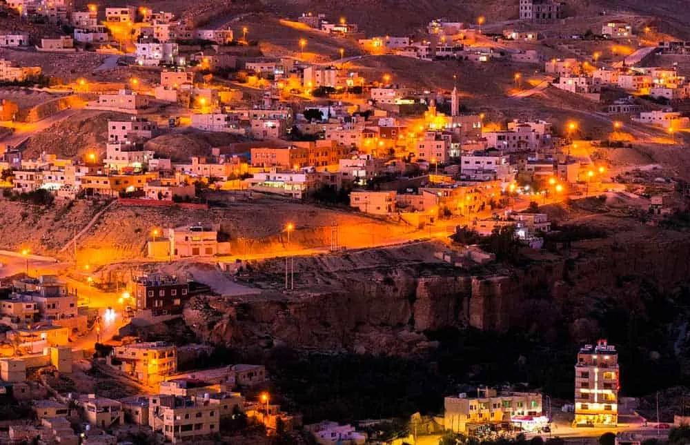 Vista nocturna de una ciudad en Jordania, iluminada por luces cálidas.