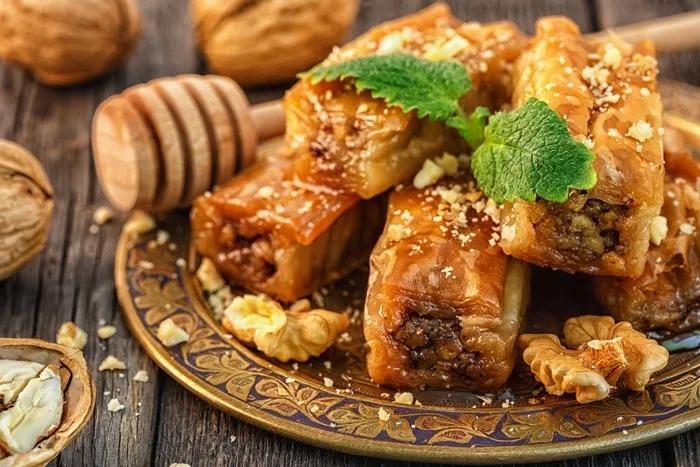 Plato de baklava con nueces y miel, decorado con hojas de menta.