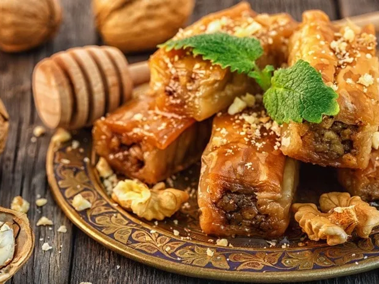 Plato de baklava con nueces y miel, decorado con hojas de menta.